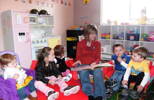 The Honourable Charlene Johnson, Minister of Child, Youth and Family Services reads a story with children during a National Child Day celebration. From Left to Right: Sylvia Evans, Mary Dunn, Lindsay Soulier, Minister Johnson, Jacob Whelan, Gabriel Tucker.