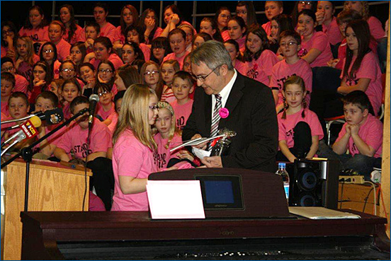 Cynthia Ball, a student at Sacred Heart Elementary in Marystown, presents the Honourable Clyde Jackman, Minister of Education with a pink T-shirt to mark "Stand Up to Bullying Day" at the school.
