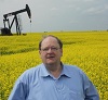 The Honourable Tom Marshall, Minister of Natural Resources, stands in a canola field with a pumpjack producing oil at a well in southeast Saskatchewan. The process of hydraulic fracturing has been used there for decades to extract oil from shale rock formations underground.