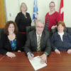 The Honourable Clyde Jackman, Minister of Education, signs a proclamation declaring February Inclusive Education Month in Newfoundland and Labrador. Pictured, from front left, are Sherry Gambin-Walsh, Executive Director of the Newfoundland and Labrador Association for Community Living (NLACL); Minister Jackman and Gail St. Croix, Vice-Chair (NLACL). From back left are: Kelly White, Executive Director of the Coalition for Disabilities and Pam Anstey, Director of Strategic Initiatives, NLACL.