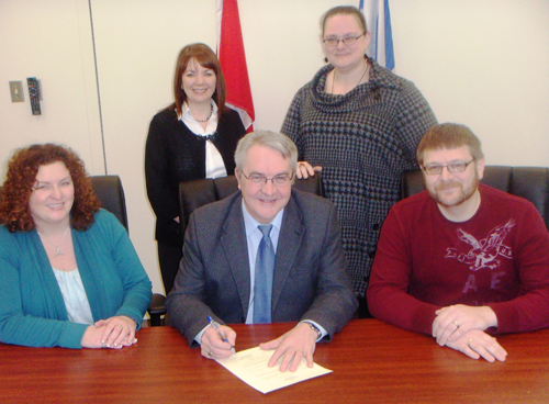 The Honourable Clyde Jackman, Minister of Education, signs a proclamation declaring February Inclusive Education Month in Newfoundland and Labrador. Pictured, from front left, are Sherry Gambin-Walsh, Executive Director of the Newfoundland and Labrador Association for Community Living (NLACL); Minister Jackman, and Guy Marsh, Finance and Communications Assistant (NLACL). From back left are Jackie Fewer-Bennett, Inclusive Education Consultant, Department of Education and Pam Anstey, Information Officer with Epilepsy Newfoundland Labrador.