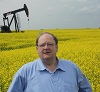 The Honourable Tom Marshall, Minister of Natural Resources, stands in a canola field with a pumpjack producing oil at a well in southeast Saskatchewan. The process of hydraulic fracturing has been used there for decades to extract oil from shale rock formations underground.